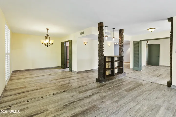 Open floorplan with gas fireplace, shutters and wood-look tile flooring throughout