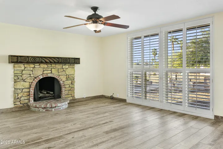 Open floorplan with gas fireplace, shutters and wood-look tile flooring throughout