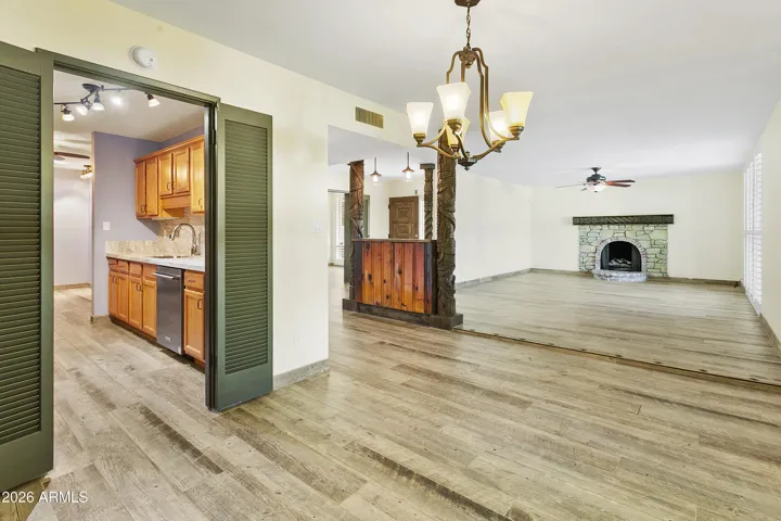 Open floorplan with gas fireplace, shutters and wood-look tile flooring throughout