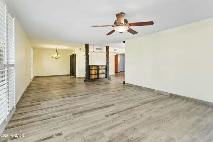 Open floorplan with gas fireplace, shutters and wood-look tile flooring throughout
