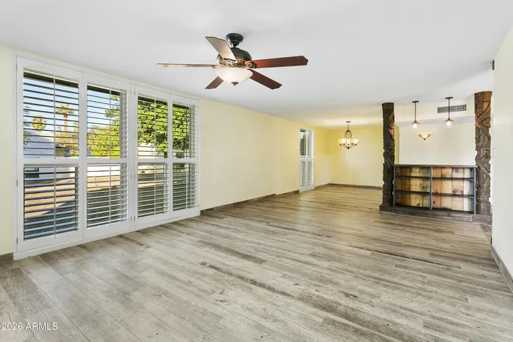 Open floorplan with gas fireplace, shutters and wood-look tile flooring throughout