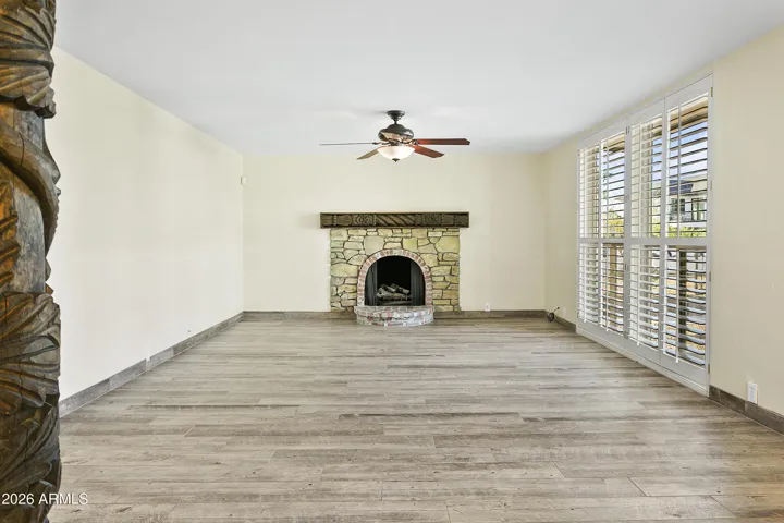 Open floorplan with gas fireplace, shutters and wood-look tile flooring throughout