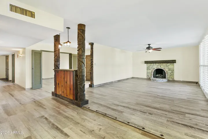 Open floorplan with gas fireplace, shutters and wood-look tile flooring throughout