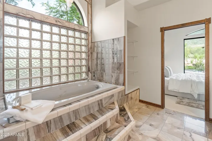 Luxury tub with jets and chandelier above