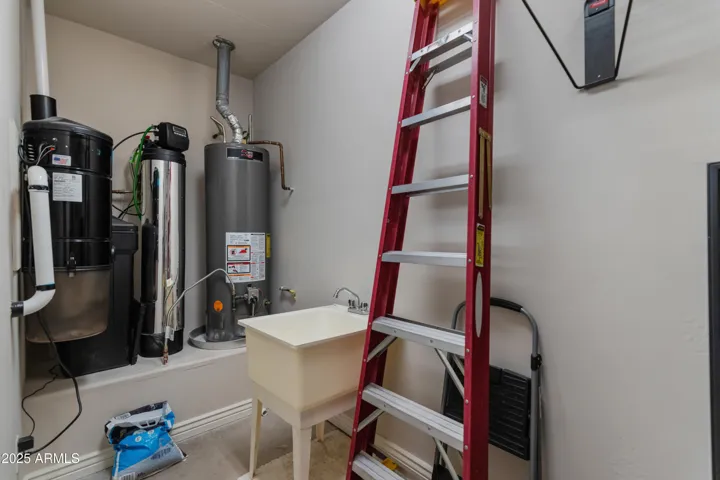 Utility room in garage featuring water heater and soft water system
