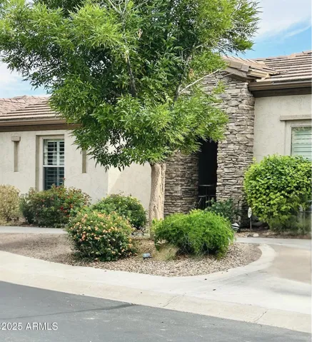 Inviting Front Exterior Featuring Brick Detail, Mature Desert Landscaping with beautiful River Rock Pathway Accents & Electric Ground Level Landscape Lighting