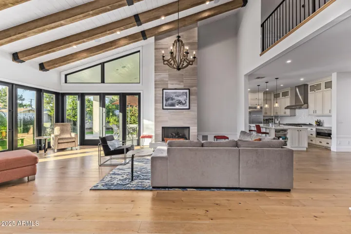 Great Room design with beautiful beamed ceilings, floor to ceiling windows/doors and wood floors throughout