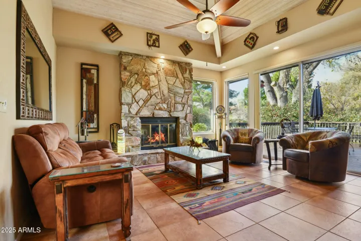 A bright living room with a cozy wood burning fireplace and a floor-to-ceiling double pane sliding door opening onto the terrace. Large windows showcase stunning views of the red rocks, creating a warm, light-filled space ideal for relaxing and enjoying the surroundings year-round.
