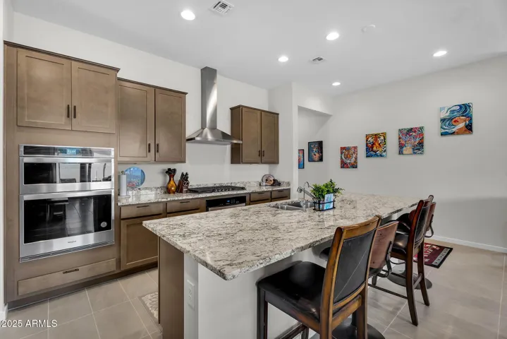 The primary kitchen features a breakfast bar with seating for four, a gas stove with a stainless steel hood, a built-in oven, and a convection microwave.