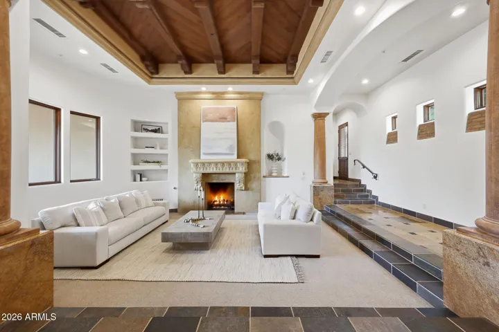Anchored by a hand-carved stone fireplace and framed by a coffered wood ceiling with exposed beams