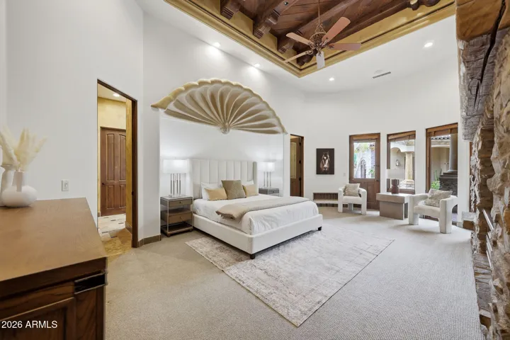 Featuring a stone fireplace with exposed wood beam ceiling detail and direct patio access
