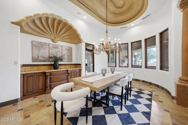 Featuring a statement chandelier, custom ceiling detail, and built-in buffet with decorative niche