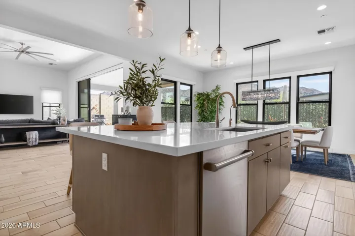 Open kitchen and dining layout designed for entertaining, featuring quartz countertops, modern cabinetry, and designer lighting. This Scottsdale luxury home offers seamless flow between cooking, dining, and living spaces