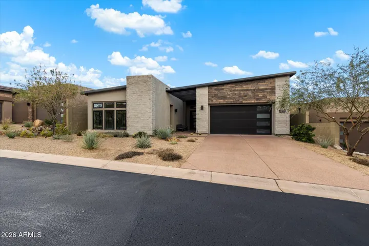 Stylish front elevation showcasing modern materials, flat rooflines, and thoughtfully designed desert landscaping. This Scottsdale luxury residence blends architectural elegance with the natural desert setting