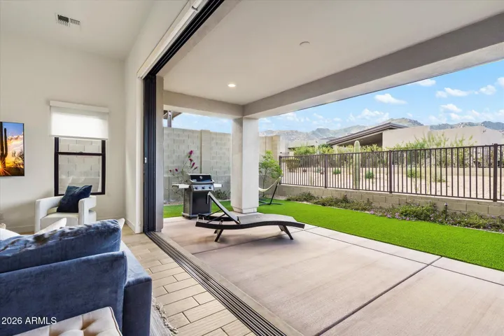 Lovely backyard showcasing wide sliding disappearing doors, covered patio, and turf lawn. Designed to maximize Scottsdale’s year-round outdoor enjoyment