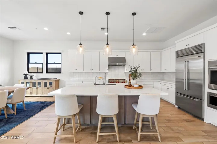 Large center island with seating, quartz surfaces, and contemporary finishes. This Scottsdale kitchen centerpiece offers ample prep space, storage, and gathering room for guests.