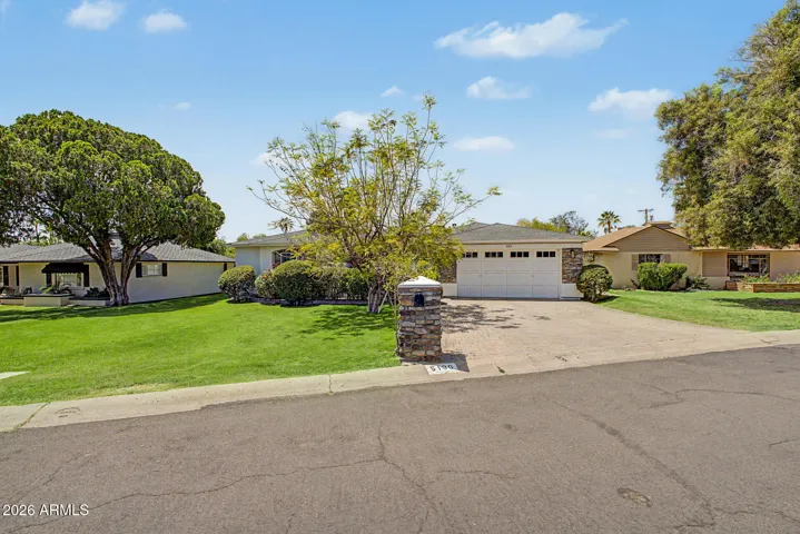 Wide-angle view of the home highlighting lush greenery, extended driveway, and clean architectural lines. This Phoenix residence offers a perfect blend of comfort, privacy, and attractive exterior design.