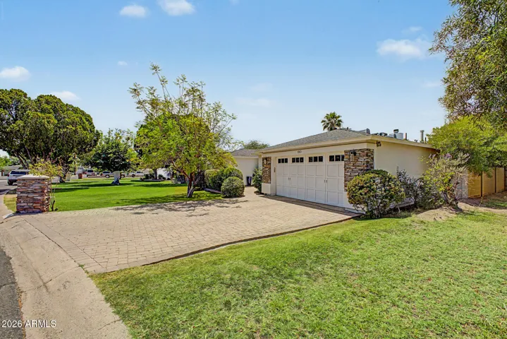 Inviting front yard with vibrant green lawn, mature trees, and manicured landscaping. This Phoenix property showcases a peaceful outdoor setting that enhances curb appeal and provides a relaxing first impression.