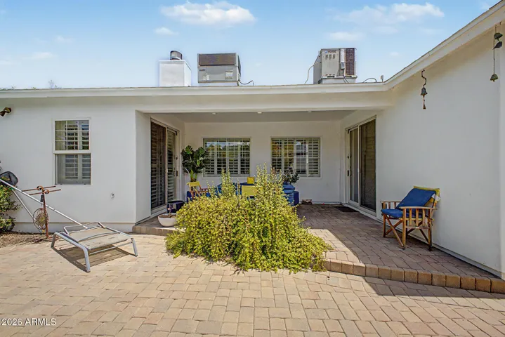 Covered patio with seating space and garden views, ideal for outdoor dining and relaxation. This Phoenix home enhances everyday living with shaded comfort and privacy.
