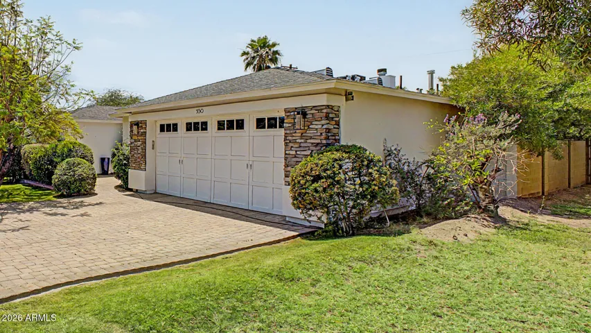 Beautiful Phoenix home exterior featuring a spacious paver driveway, two-car garage, and stone accent details. This well-maintained property offers excellent curb appeal with mature landscaping and a welcoming residential setting.
