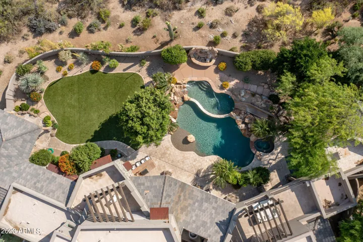 An overhead view reveals the estate’s true scale, privacy, and connection to the surrounding desert landscape. The lower pool with its slide and the sweep of lush turf are clearly visible, showing how the grounds are layered and thoughtfully planned.