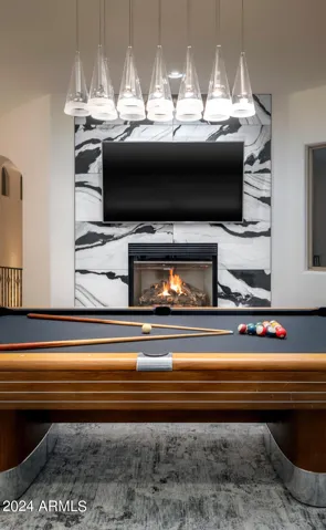 Bold stone fireplace, black-felt pool table, and balcony views set the scene for play.