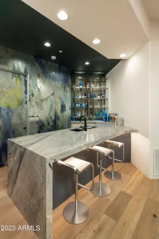 Quartzite waterfall bar anchors the space, ideal for gathering before flowing outdoors to the pool and spa. A flexible, enclosed room sits just off the media room with direct access to a full pool bath, offering versatility as a guest bedroom, wellness room, or private studio.