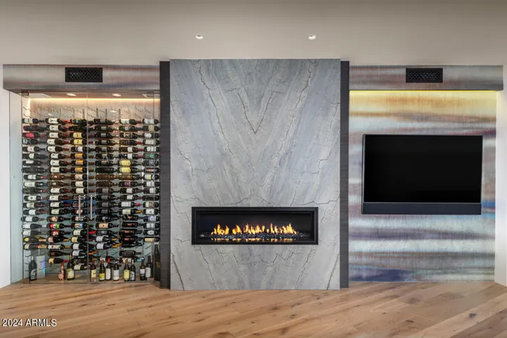 Glass-enclosed, temperature controlled wine cellar pairs with linear fireplace faced with natural stone for a striking architectural moment.