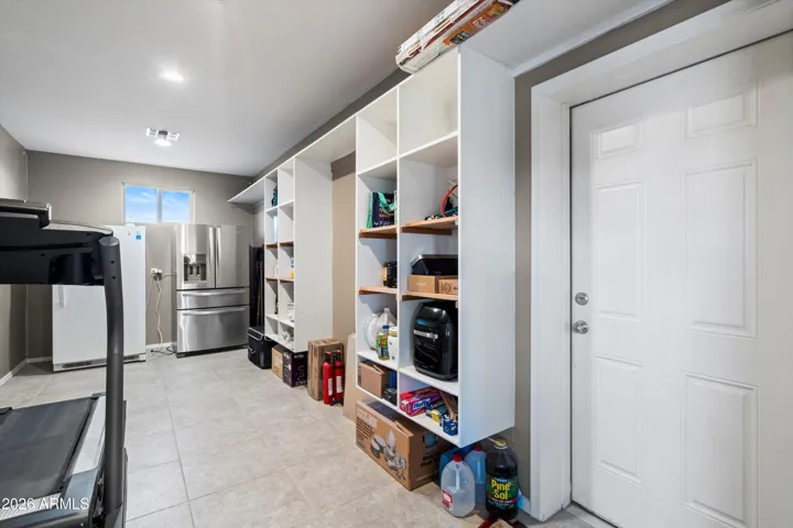 Spacious walk-in pantry with extensive shelving offers flexibility for food storage, bulk items, or household organization. Includes an additional refrigerator and freezer, both conveying with the home, and provides direct access to the garage.