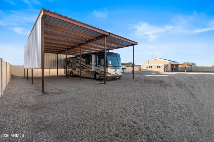Large RV carport with gravel base and generous clearance. Designed for motorhomes or trailers. RV shown does not convey.