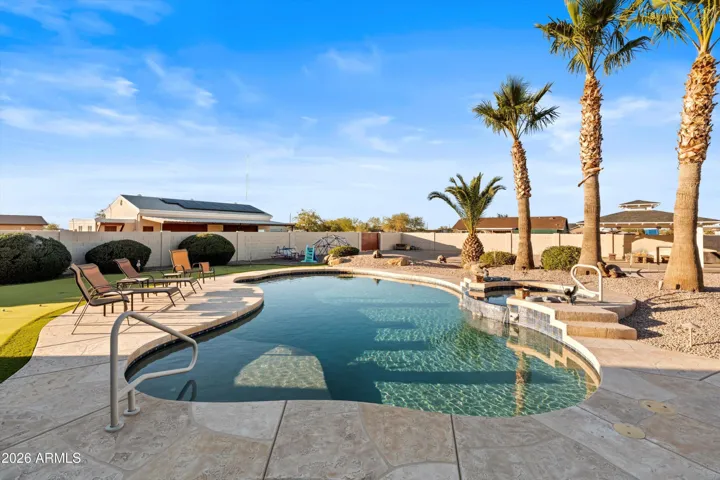 Heated and cooled pool with attached spa, framed by mature palm trees and generous deck space. Designed for both entertaining and everyday enjoyment.