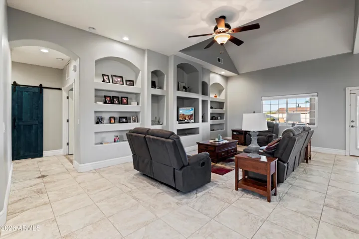 The great room features vaulted ceilings, tile flooring, ceiling fans, and custom wall niches. Open to the kitchen, this space is designed for everyday living while maintaining a clean, open feel.