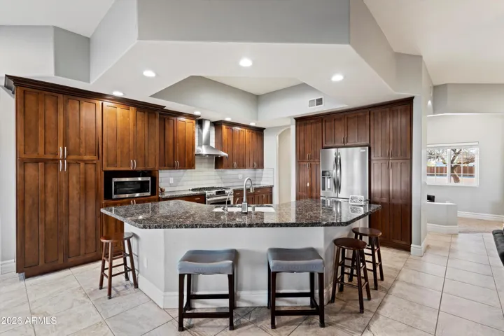 The kitchen offers generous counter space with granite surfaces, rich wood cabinetry, and stainless steel appliances. The layout provides excellent flow between the kitchen, living area, and dining space, supporting both daily living and entertaining.