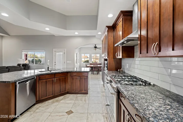 This view highlights the open connection between the kitchen and dining area. Vaulted ceilings, recessed lighting, and tile flooring throughout create a bright, cohesive space with easy movement between rooms.