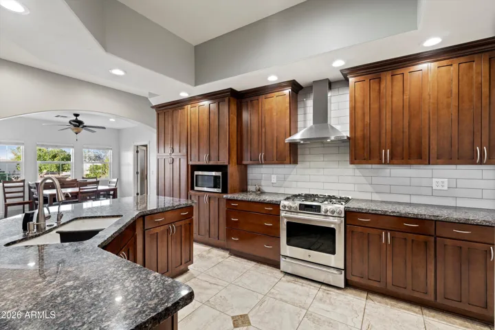 This spacious kitchen features rich wood cabinetry, granite countertops, stainless steel appliances, and a large center island with seating. Open sightlines connect the kitchen to the main living areas, making it ideal for both everyday living and hosting.