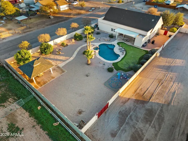 Aerial focused on the main residence featuring the pool, heated spa, gazebo, and landscaped yard. Shows how the outdoor living areas connect seamlessly to the home while remaining private within the property.