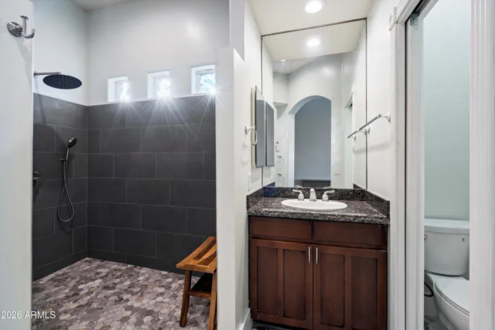 The primary bathroom features a granite-topped vanity with ample storage and updated fixtures. Clean finishes and thoughtful design create a functional space that connects seamlessly to the shower and closet.