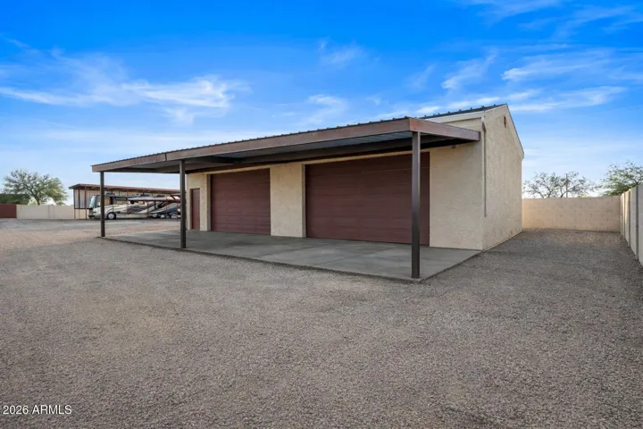 Alternate view of the detached shop showing covered workspace and access doors. Designed for functionality and easy equipment movement.