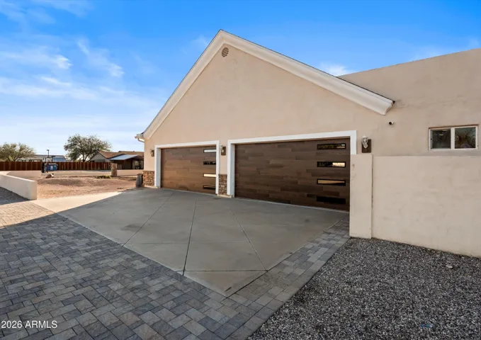 The four-car garage features modern doors and a wide driveway, offering ample parking and easy access. Designed for functionality while complementing the home’s exterior style.