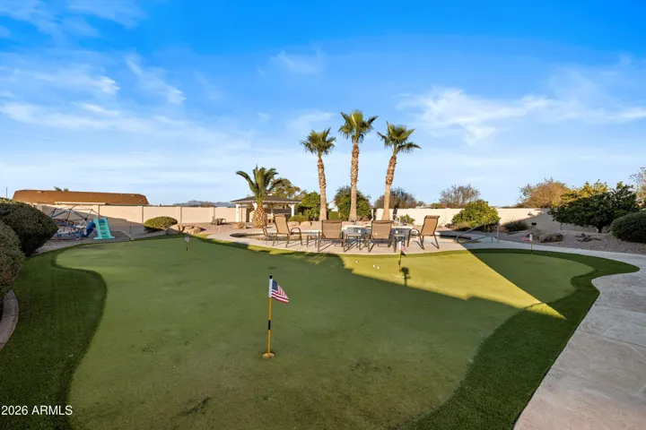 Spacious backyard featuring a professionally installed putting green, mature palm trees, and open sightlines across the property, creating a private and functional outdoor retreat.