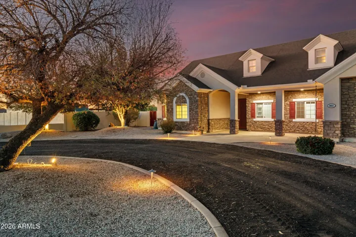 The front of the home welcomes you with classic architectural detail, stone accents, and warm exterior lighting. A circular drive and mature landscaping create a strong first impression while offering easy access and generous parking.