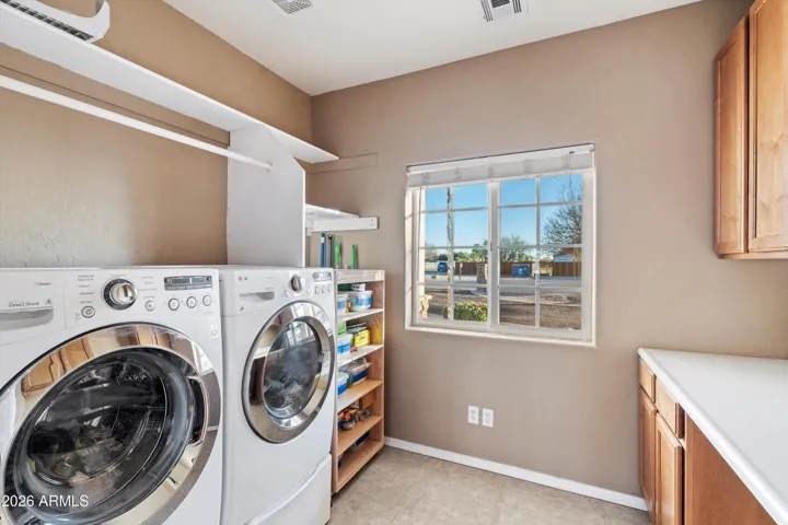 Dedicated laundry room with shelving and hanging space for clothes. Washer and dryer are included, providing a move-in-ready setup with practical organization.