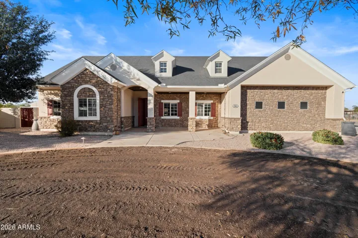 The front of the home features timeless stone accents, clean architectural lines, and a welcoming covered entry. Mature landscaping and a wide approach create a strong first impression from the moment you arrive.