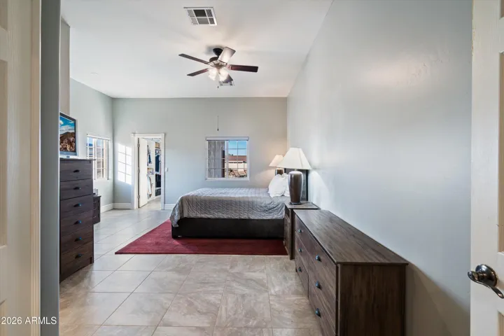 The primary bedroom offers a generous layout with tile flooring, soft natural light, and a ceiling fan for comfort. This space provides room for larger furniture while maintaining a calm, private feel separate from the rest of the home.