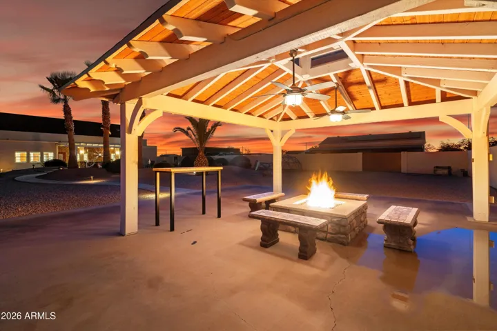 The covered gazebo creates a comfortable outdoor gathering space featuring ceiling fans, lighting, and a built-in gas fire pit. Ideal for evenings outdoors, this area adds another layer of livability to the backyard setting.