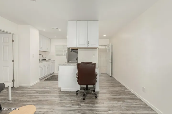 View of front door, desk & kitchen from great room dining area.