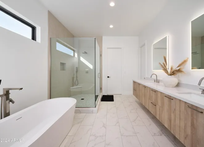 Luxurious Primary Bathroom (Primary Bedroom en-suite) featuring a dual vanity with a soaking tub and a stand-in shower.
