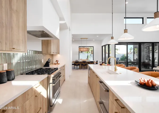 Fully equipped kitchen boasting high-end stainless steel appliances and a large island offering bar seating overlooking the formal dining area.