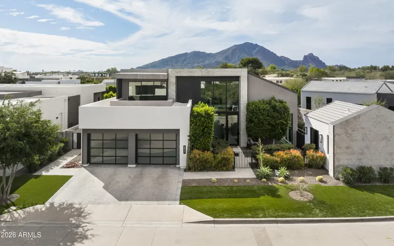 Street view of this stunning residence in a prestigious guard-gated community with a highly desirable central location. The home features a 3-car tandem garage, a private gated entry leading into the front courtyard, and a casita thoughtfully positioned at the front of the home behind its own gated entrance.
