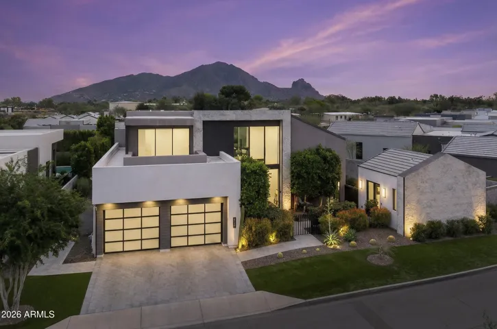 Street view of this stunning residence in a prestigious guard-gated community with a highly desirable central location. The home features a 3-car tandem garage, a private gated entry leading into the front courtyard, and a casita thoughtfully positioned at the front of the home behind its own gated entrance.